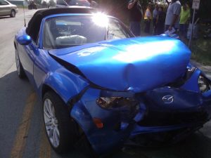 Blue car with major front end damage after an accident.